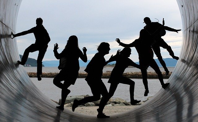 Das Bild zeigt sechs Personen, die in einer Röhre stehen und gemeinsam Spaß haben, in denen sie versuchen die Außenwände hochzulaufen. Durch die Lichtverhältnisse sieht man nur ihre Umrisse. © Servicestelle Jugendbeteiligung e. V., 2021